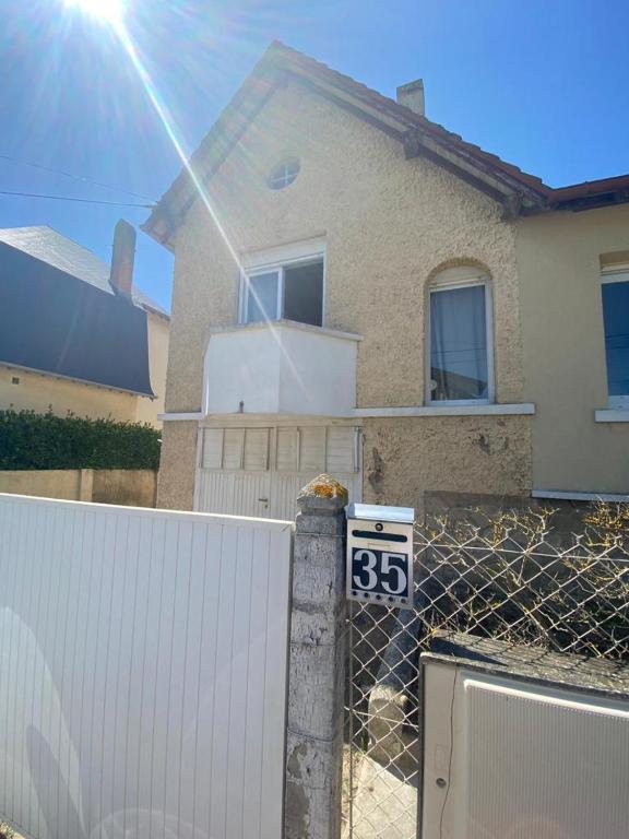 a fence in front of a house with a white gate at La plage au bout du jardin &#47; Sword Beach cottage in Hermanville-sur-Mer