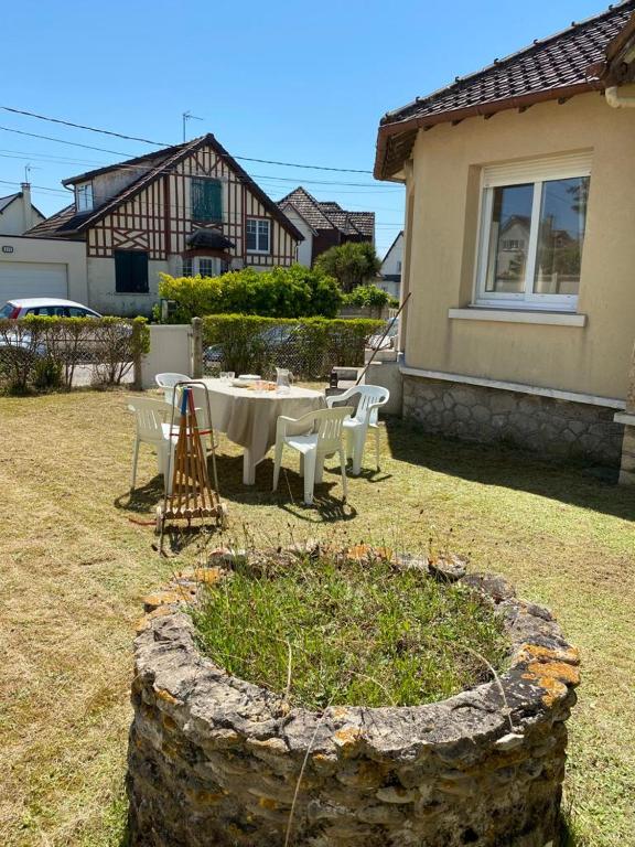 a table and chairs in the yard of a house at La plage au bout du jardin &#47; Sword Beach cottage in Hermanville-sur-Mer
