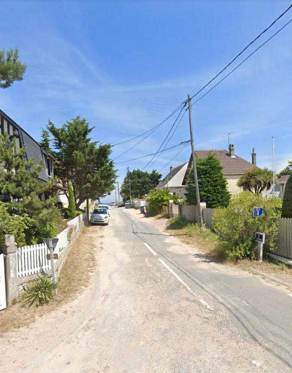 Une rue avec des maisons et une voiture sur la route dans l'établissement La plage au bout du jardin / Sword Beach cottage, à Hermanville-sur-Mer