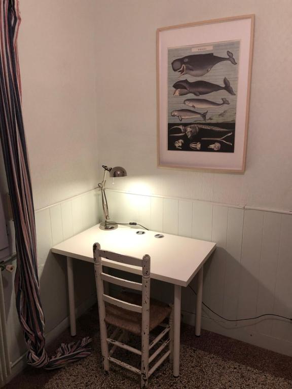 a desk with a lamp and a chair in a room at La plage au bout du jardin &#47; Sword Beach cottage in Hermanville-sur-Mer