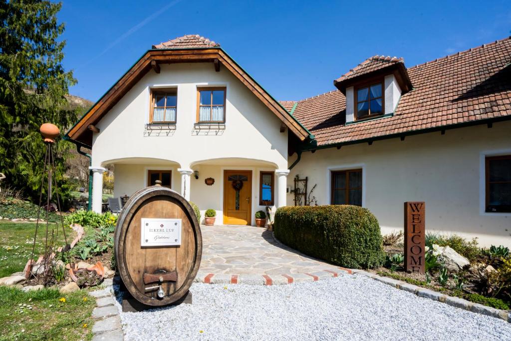 a house with a large wooden barrel in front of it at Weinberghof Ilkerl-Luf in Krems an der Donau