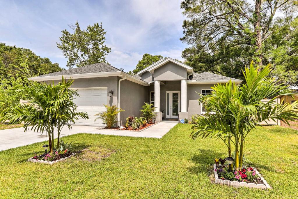 a house with two palm trees in a yard at St Pete Escape with Patio and Yard 6 Mi to Beach in St Petersburg