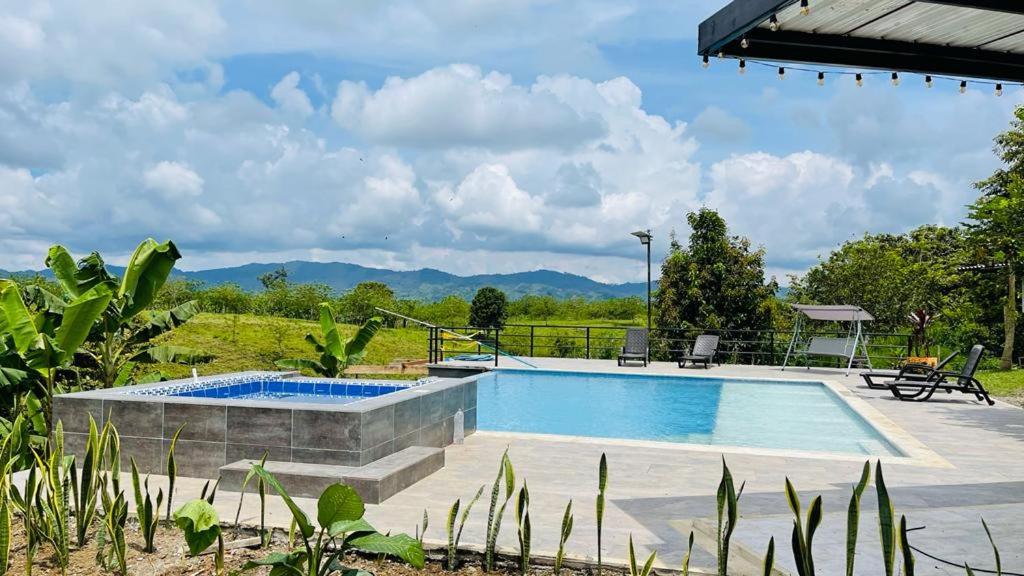 a swimming pool in a yard with mountains in the background at ORIGEN FINCA HOTEL in Quimbaya