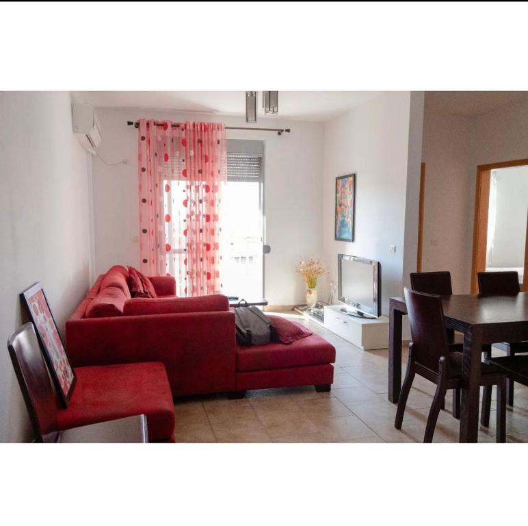 a living room with a red couch and a table at Agaraj apartament in Orikum