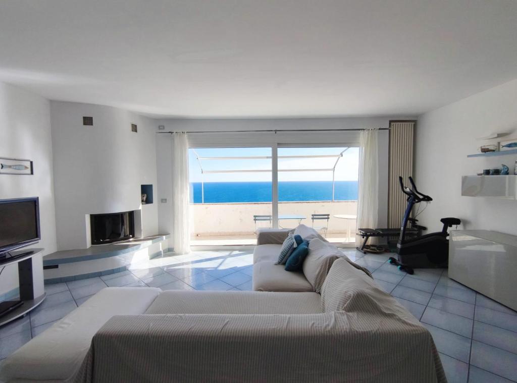 sala de estar con sofá y vistas al océano en Villa Ischia Attico sul mare a Verezzi, en Borgio Verezzi
