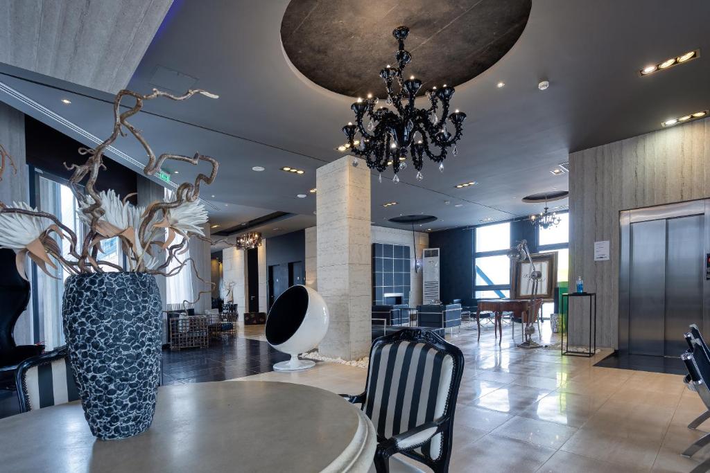 a lobby with a table and a chandelier at Gallery Art Hotel in Tríkala