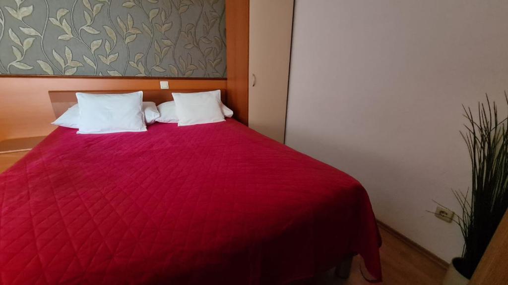 a red bed with two white pillows in a room at SOBE/ROOMS RIVA in Zadar