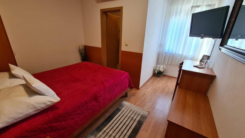a bedroom with a red bed and a flat screen tv at SOBE/ROOMS RIVA in Zadar