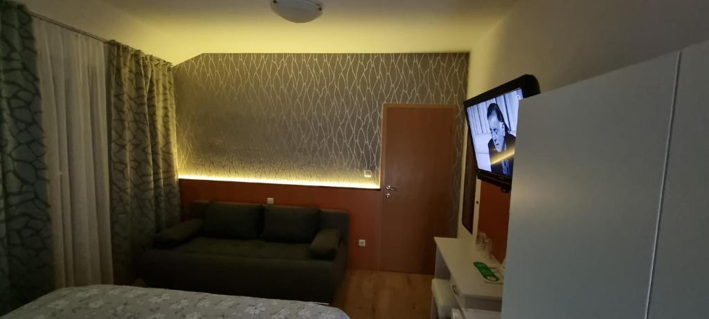 a bedroom with a bed and a couch and a television at SOBE/ROOMS RIVA in Zadar