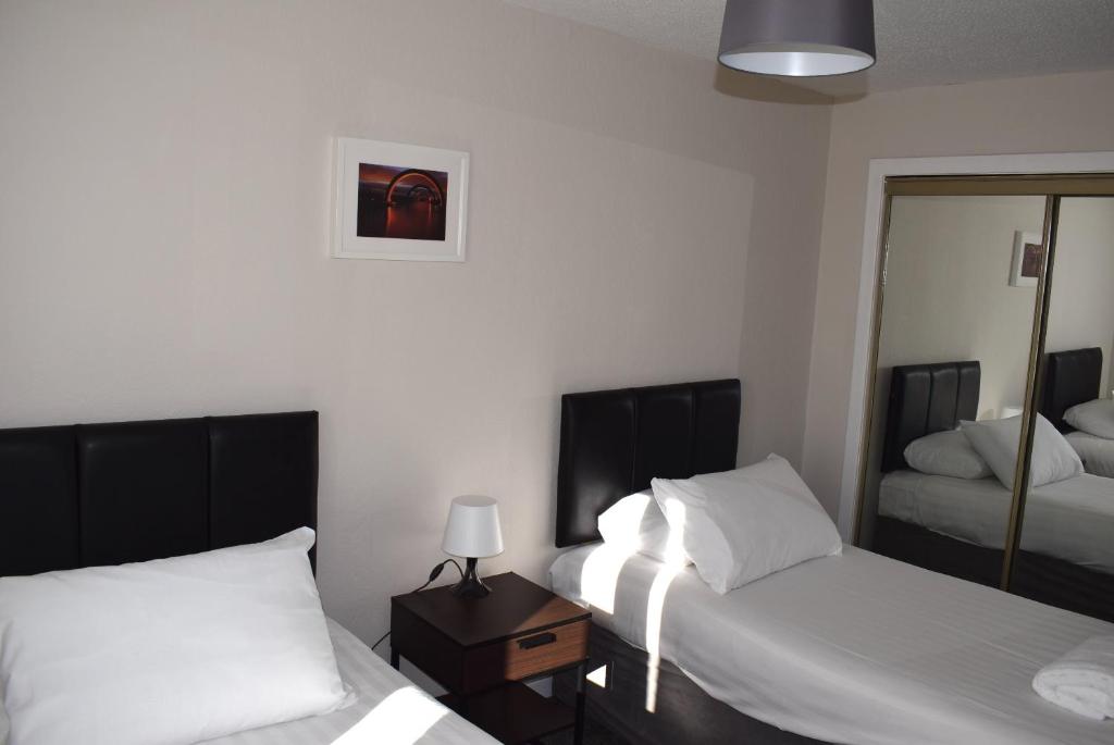 a hotel room with two beds and a mirror at Kelpies Serviced Apartments- Abbotsford in Falkirk