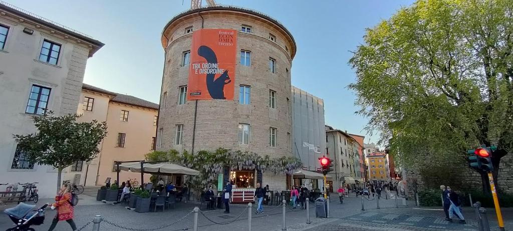 un bâtiment avec une grande tour au milieu d'une rue dans l'établissement Torrione Trento, à Trente