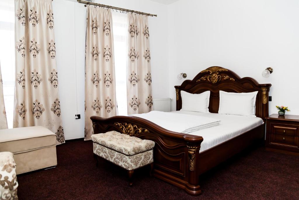 a bedroom with a bed and a chair and curtains at VILA Corviniana in Hunedoara