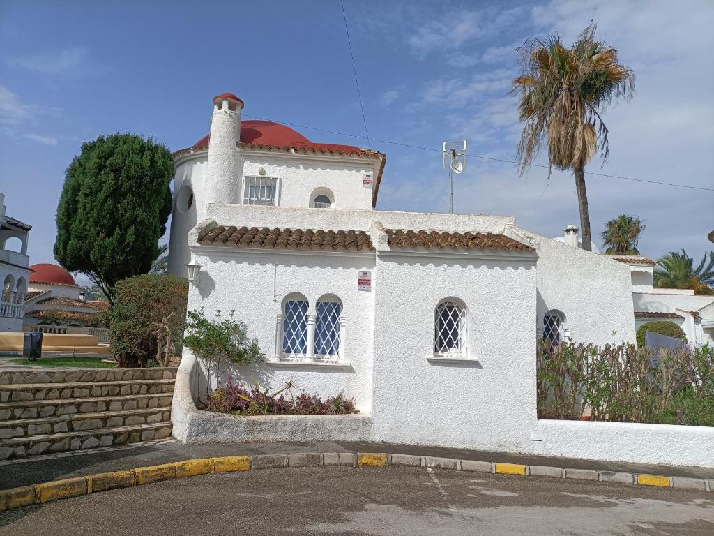 une maison blanche avec un palmier en face dans l'établissement Chalet en urbanizacion, à Dénia