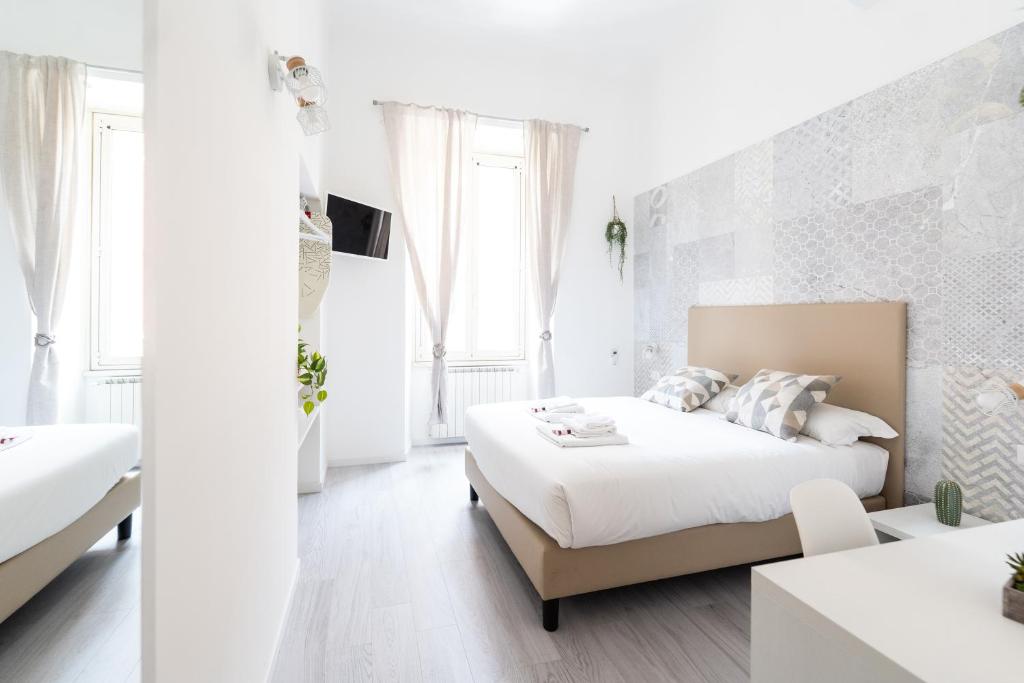 a white bedroom with a bed and a table at White Gioberti Guesthouse in Rome