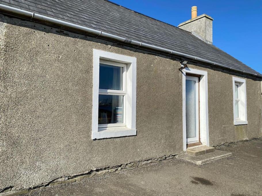 Una casa con dos ventanas en el lateral. en 2 Bedroom house overlooking Pierowall Bay, Westray, en Pierowall