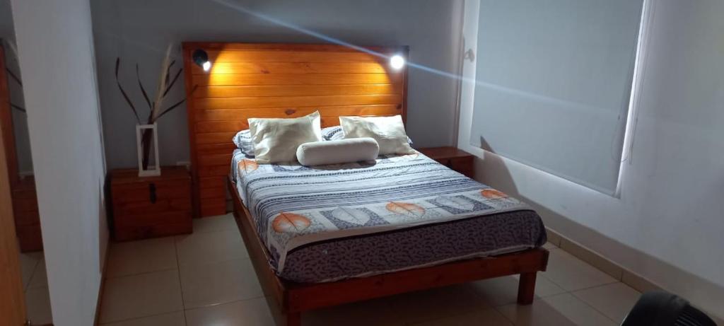 a small bed with a wooden headboard in a room at Eljacaranda_ in Gualeguay