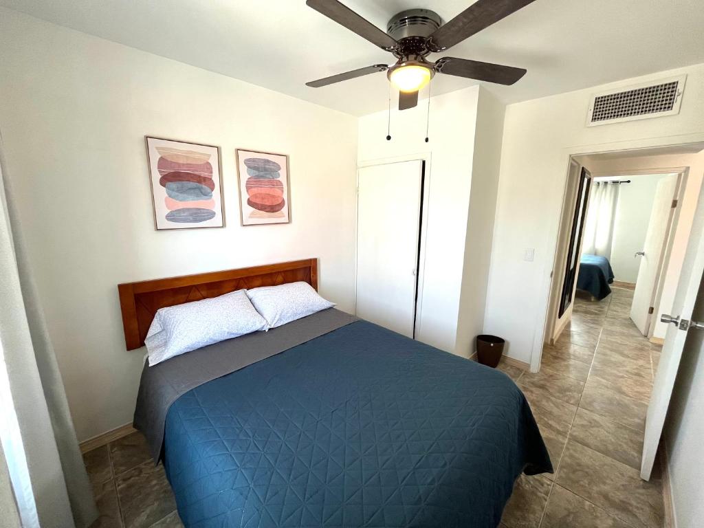 1 dormitorio con 1 cama azul y ventilador de techo en Departamento Los Cedros en Ciudad Juárez