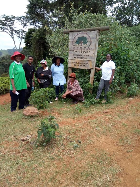 a group of people standing next to a sign at Thayo Place in Nyeri