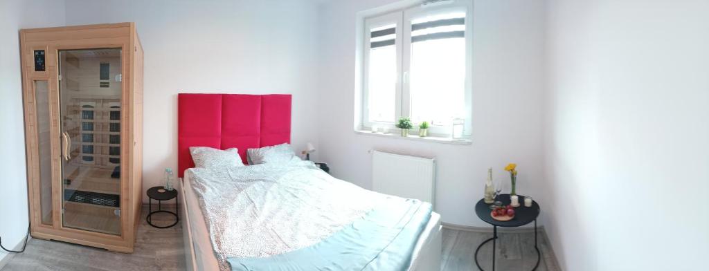 een slaapkamer met een bed met een rood hoofdeinde bij Apartament z Sauna i Jacuzzi in Radom