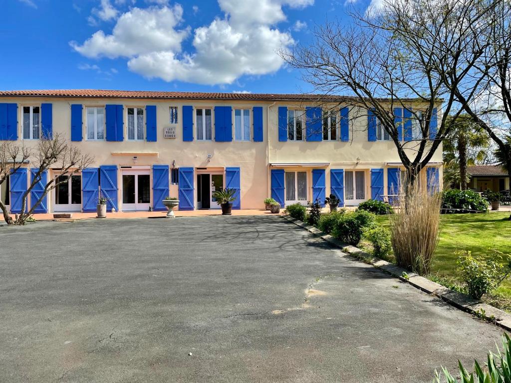 un gran edificio blanco con persianas azules en Les trois cèdres, en Saint-ouen-dʼAunis