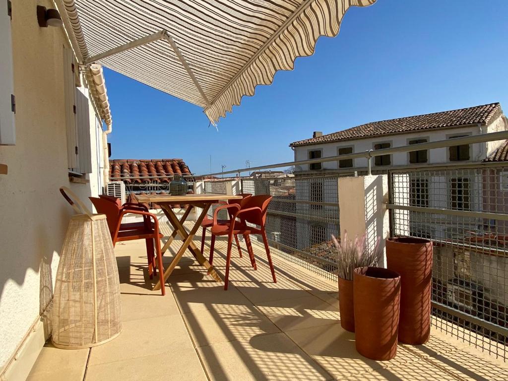 a patio with a table and chairs on a balcony at La Terrasse sur les Toits in Narbonne