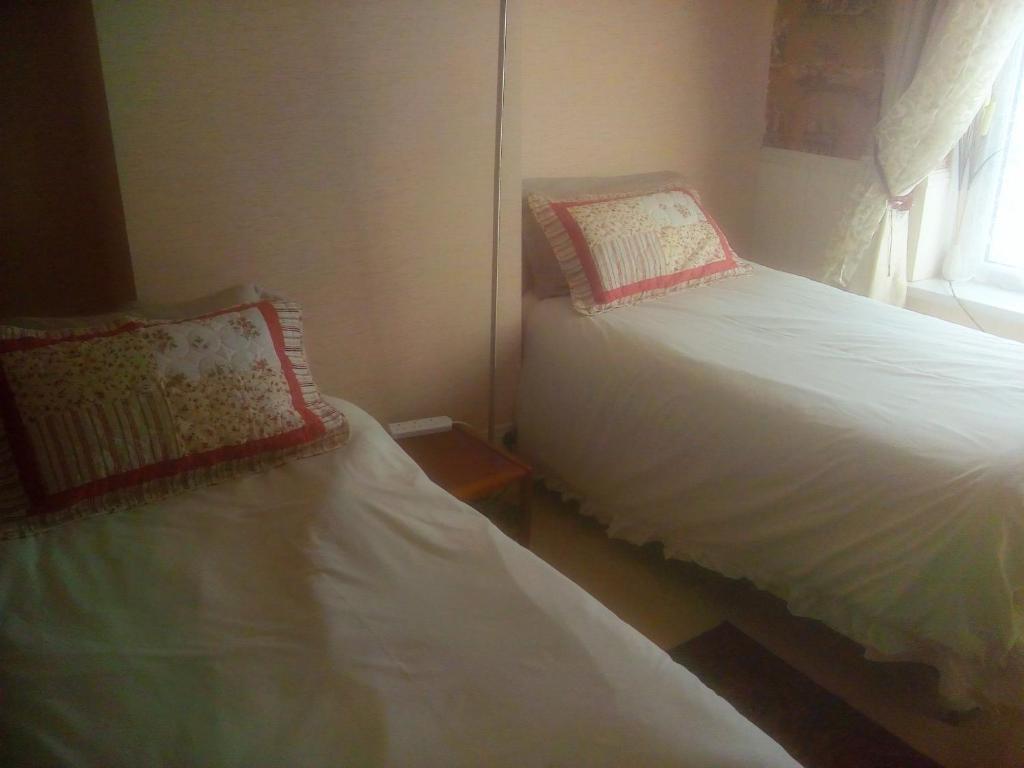 two beds in a small room with a window at The Principality 2 Singles Bedroom in Cardiff