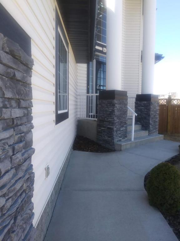 a house with a stone wall next to a sidewalk at 680 SQ FT Private Space With Ensuite Bathroom in Calgary