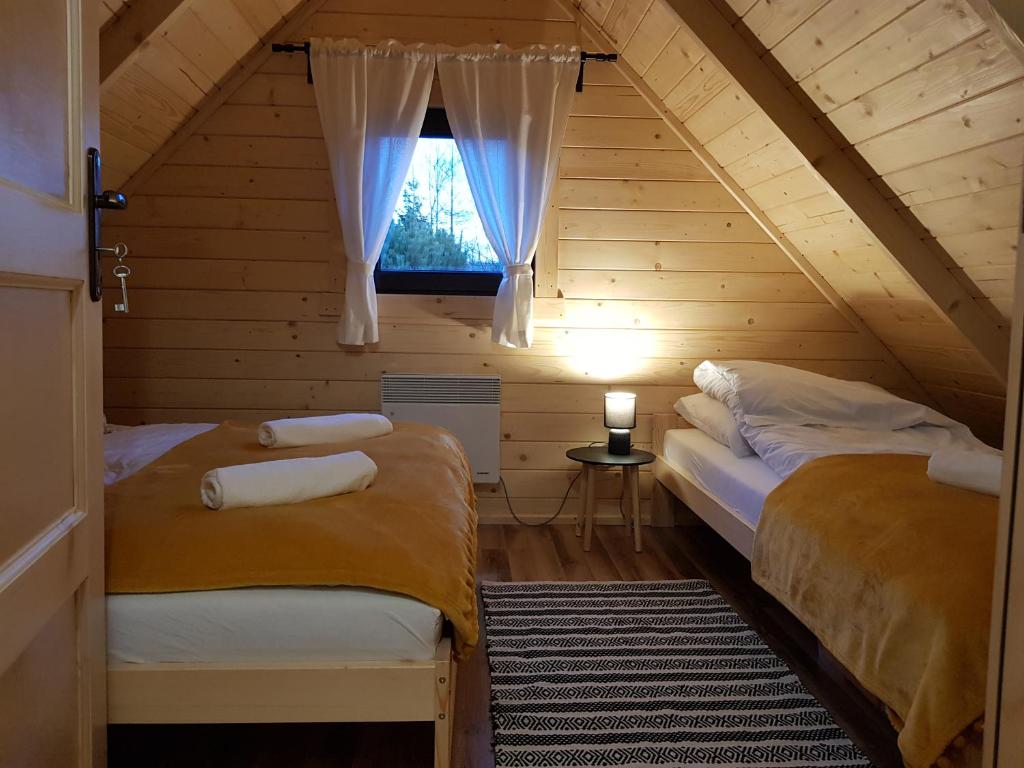 a attic room with two beds and a window at Chata Rafusa pod Śnieżnikiem in Stronie Śląskie