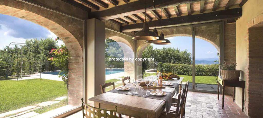 een eetkamer met een tafel en uitzicht op de tuin bij Luxury Villa Among Vineyards in Arezzo