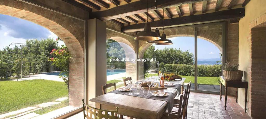 a dining room with a table and a view of the yard at Luxury Villa Among Vineyards in Arezzo