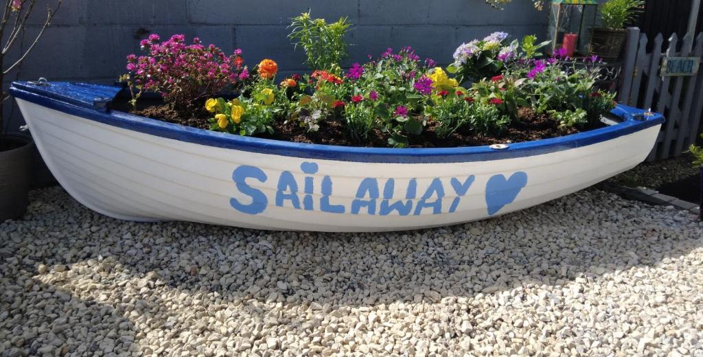 a boat filled with flowers sitting on the ground at Sailaway in Carbis Bay