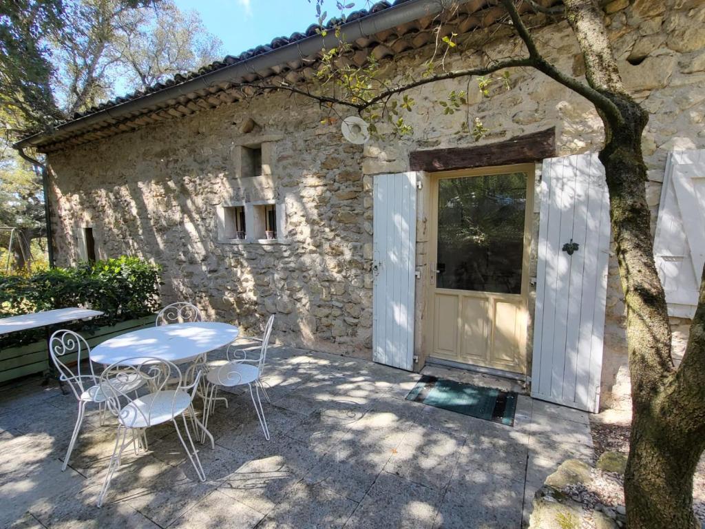 een tafel en stoelen voor een stenen gebouw bij La Cassine, gîte des Lucioles en Provence in Montségur-sur-Lauzon