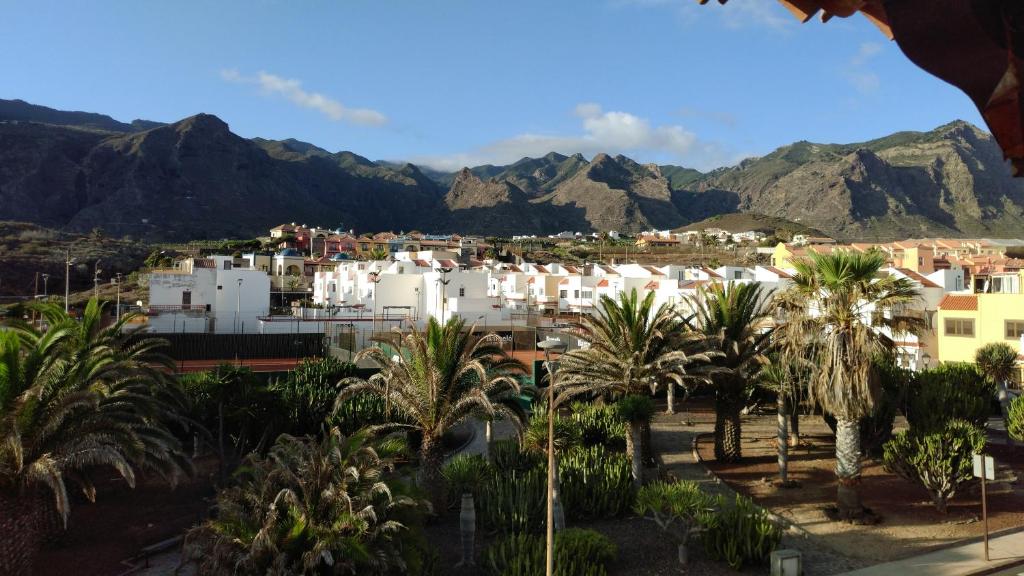 een stad met palmbomen en bergen op de achtergrond bij Schöne Ferienwohnung auf Teneriffa in Los Silos
