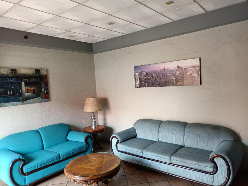 una sala de espera con dos sofás azules y una mesa en Hotel México en Morelia