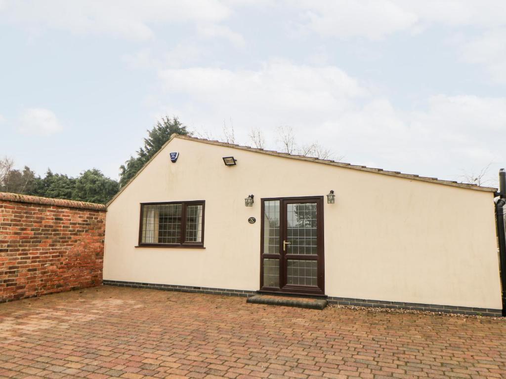 um edifício branco com uma porta preta numa entrada de tijolos em Millers Retreat em Bolsover