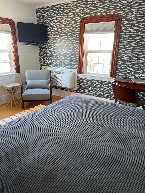 a bedroom with a bed and a chair and a desk at The Archie & Isidore Hotel in Chéticamp