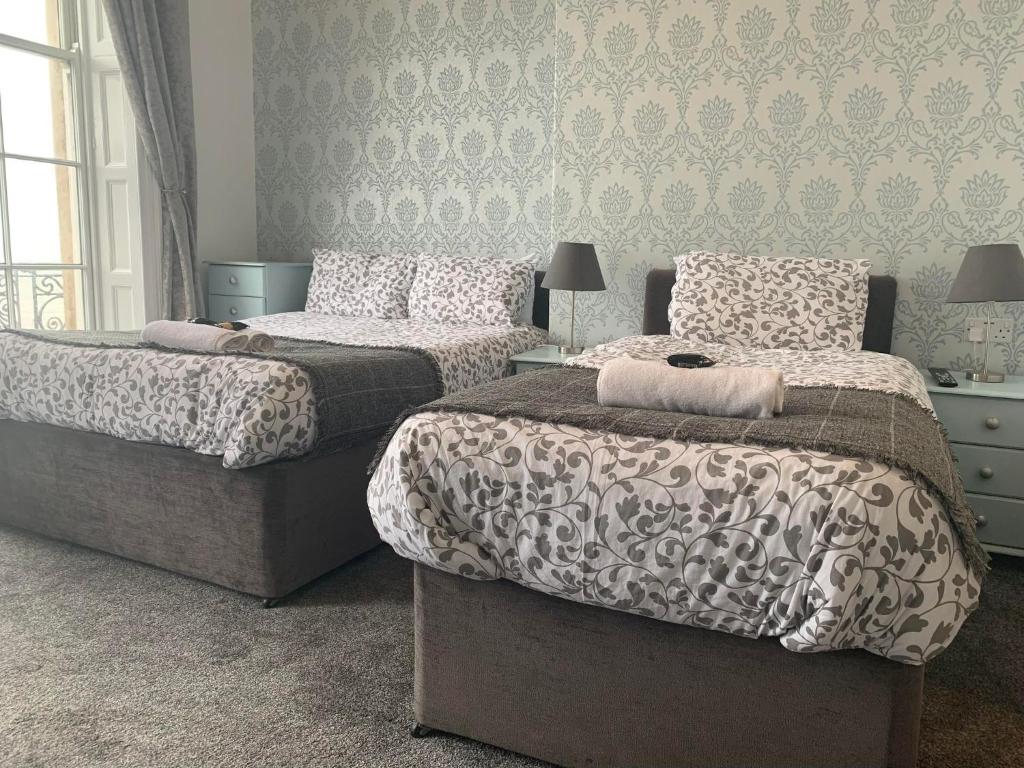 a bedroom with two beds and a patterned wall at The Jubilee Hotel - with Spa and Restaurant and Entertainment in Weymouth
