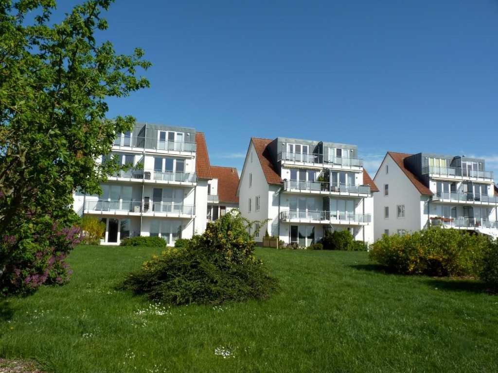 una fila de edificios de apartamentos blancos en un campo verde en Ferienwohnung "Müritzuferblick" Objekt ID 12112-5 en Waren