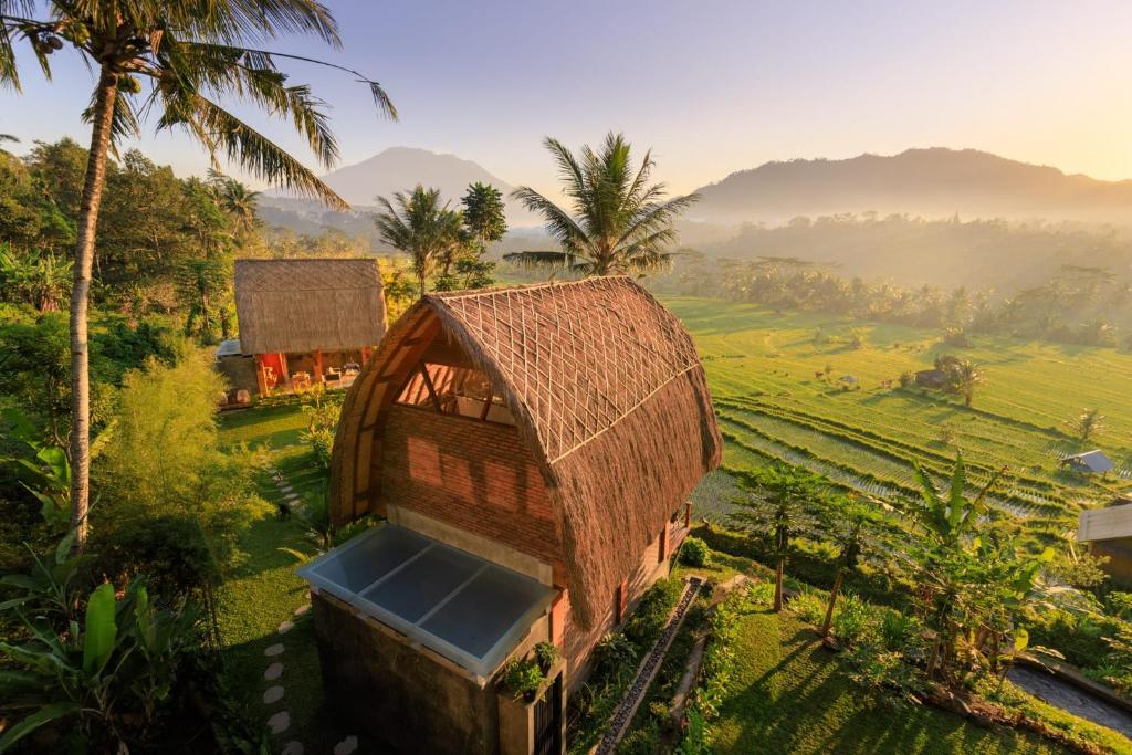 a small house with a straw roof on a field at Like living in a romantic Balinese painting in Sidemen