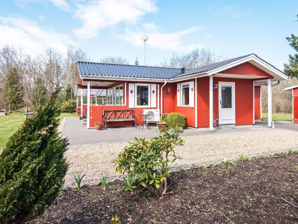 a red house with a patio in a yard at 6 person holiday home in Hemmet in Falen