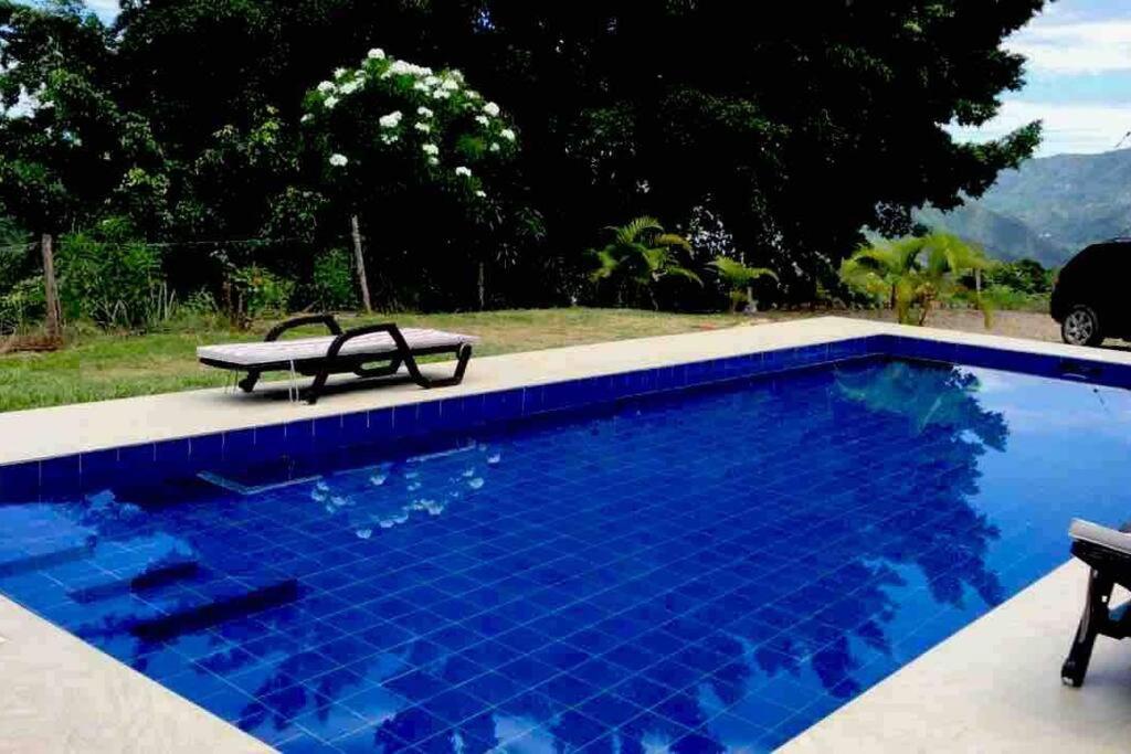 uma piscina azul com um banco ao lado em LINDA CASA/PISCINA/VISTASUPERWIFI/DIRECTV/12PERSONAS em Anapoima