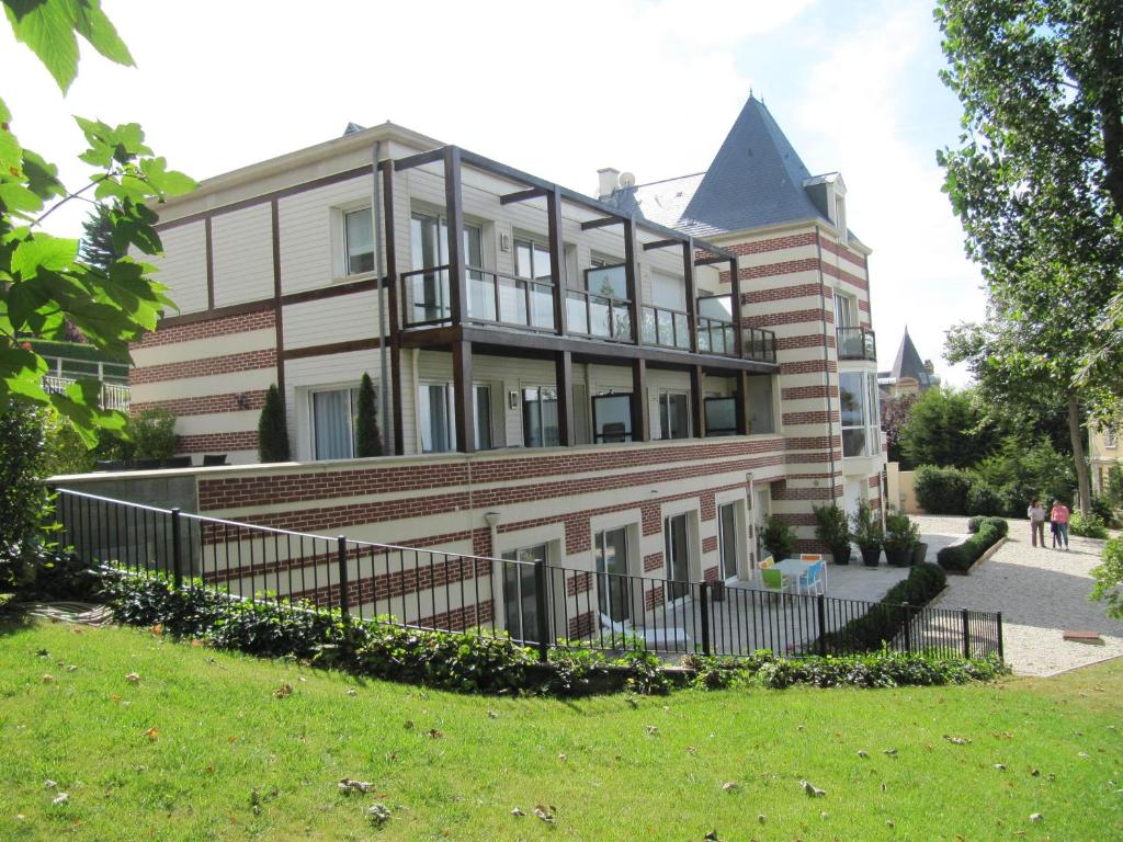 un bâtiment avec une clôture devant lui dans l'établissement Villa Régina, à Trouville-sur-Mer