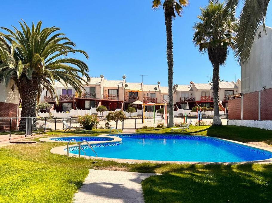 una piscina con palmeras en un complejo en Genial Casa en Bahía Inglesa en Bahía Inglesa