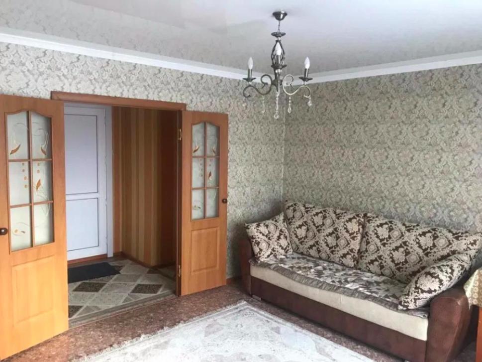 a living room with a couch and a chandelier at Апартаменты на Утепбаева 1 in Semey