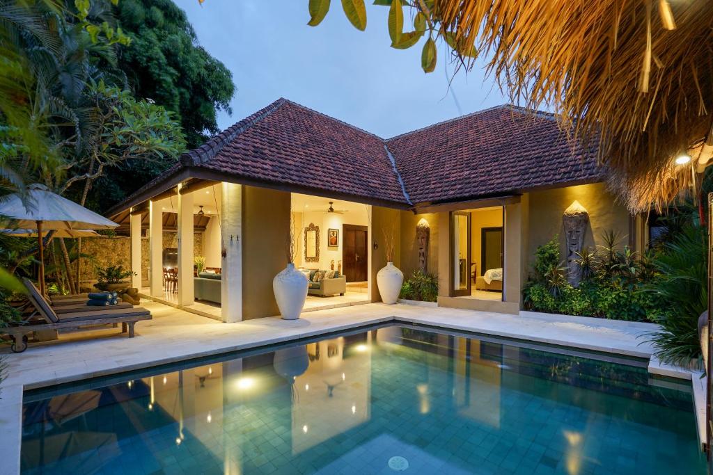 a villa with a swimming pool in front of a house at Asrina Villa's Seminyak in Seminyak