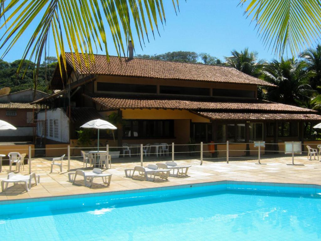 um resort com uma piscina com cadeiras e guarda-sóis em Búzios Internacional Apart Hotel em Búzios
