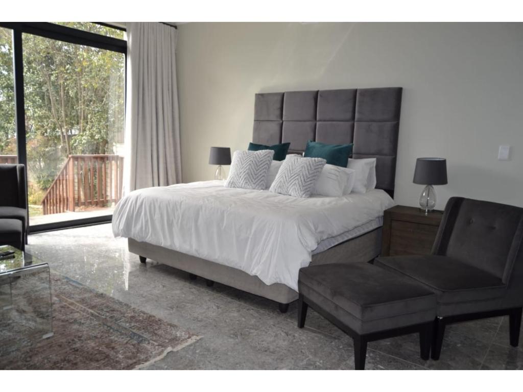 a bedroom with a large bed and a chair at Furaha Guest Lodge in Johannesburg