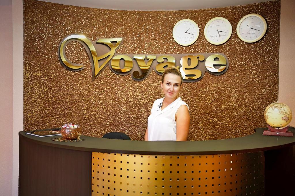 a woman standing in front of a counter with clocks at Mini Hotel Voyage in Novokuznetsk