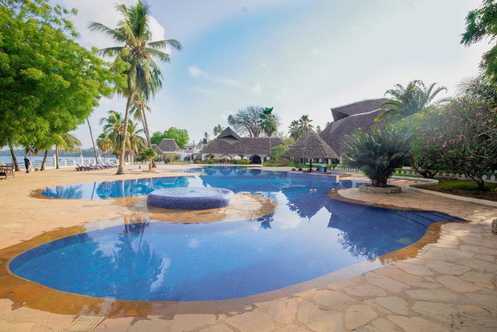 basen w ośrodku z niebieską wodą i palmami w obiekcie Zanzibar Beach Resort w mieście Zanzibar