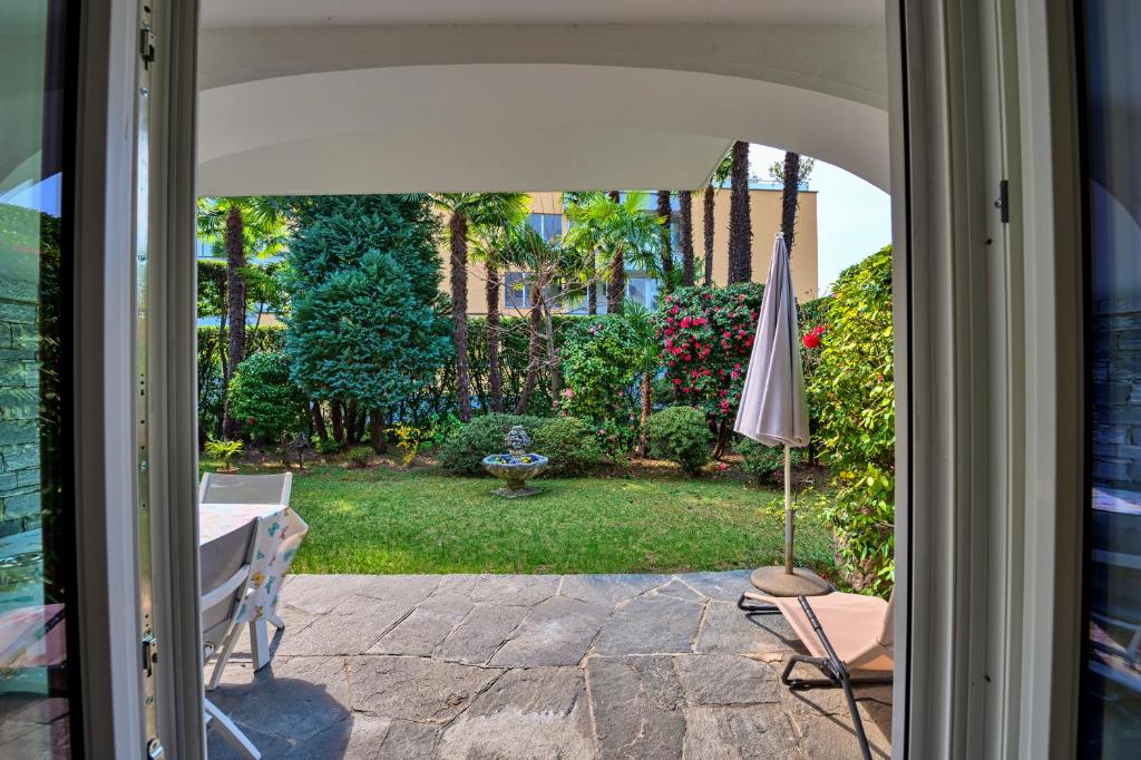 eine offene Tür zu einer Terrasse mit einem Sonnenschirm in der Unterkunft Casa Liliane in Ascona